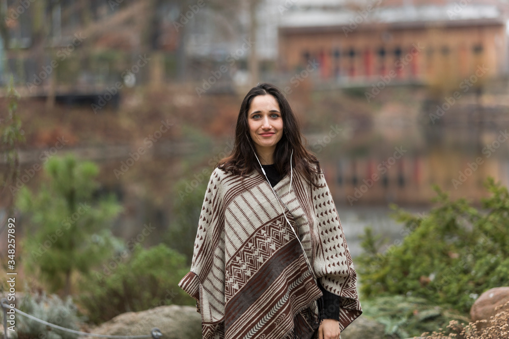 Attractive young Indian woman dressed in poncho smiling outdoors. Front view. Attractive young Indian woman dressed in poncho smiling outdoors. Front view.