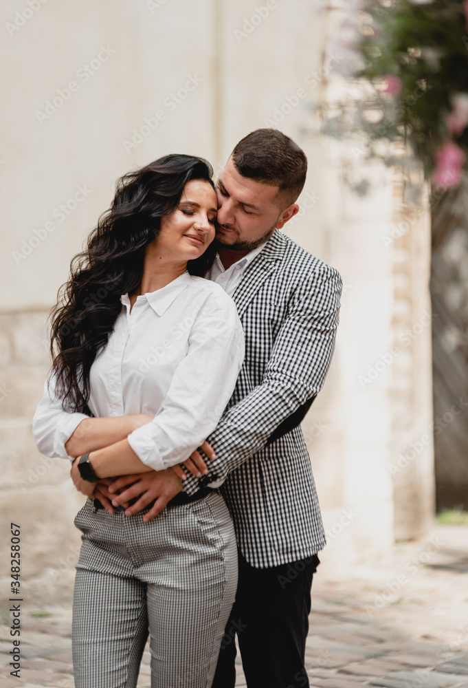 stylish middle-aged couple gently hugging on the streets of the old city,the guy gently kisses the girl,cellular clothing stylish middle-aged couple gently hugging on the streets of the old city,the guy gently kisses the girl,cellular clothing