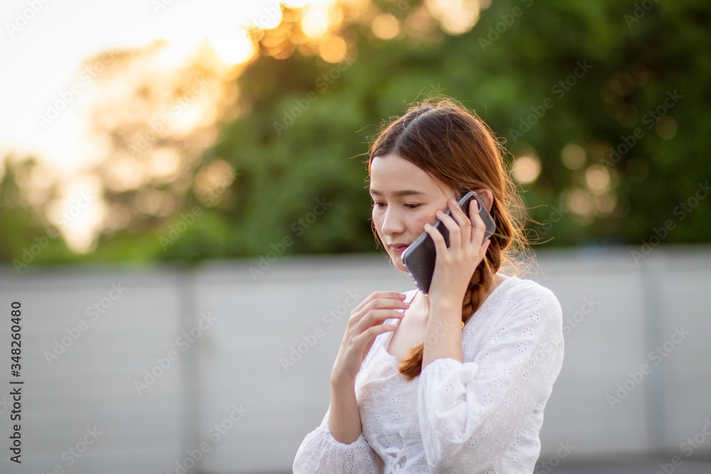 Displeased and disappointed girl with a mobile phone stands in parking lot . In the evening the sunset was orange. copy space. Displeased and disappointed girl with a mobile phone stands in parking lot . In the evening the sunset was orange. copy space.