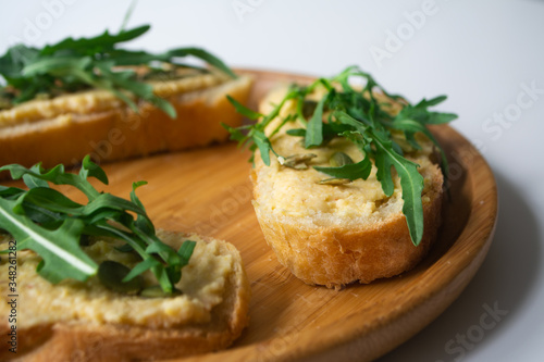 Sandwich of toasted bread slices with classic chickpea hummus spread, roasted pumpkin seeds and fresh arugula