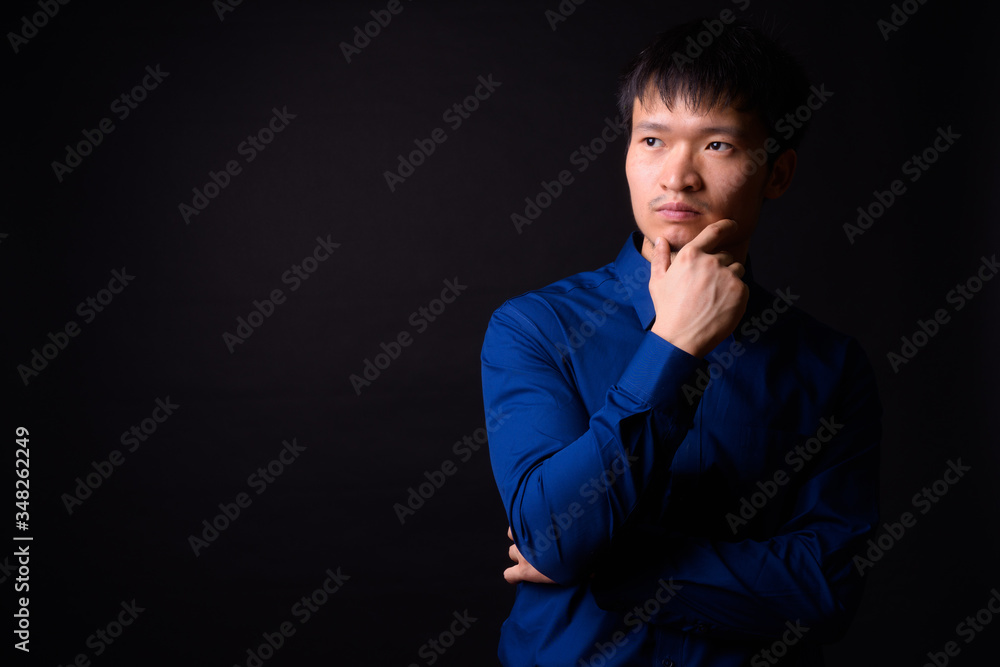 Portrait of young Asian businessman thinking and looking away