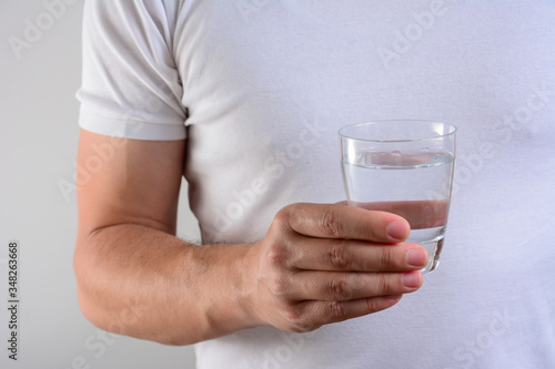 Mid adult man holding a glass of water. Close up.
