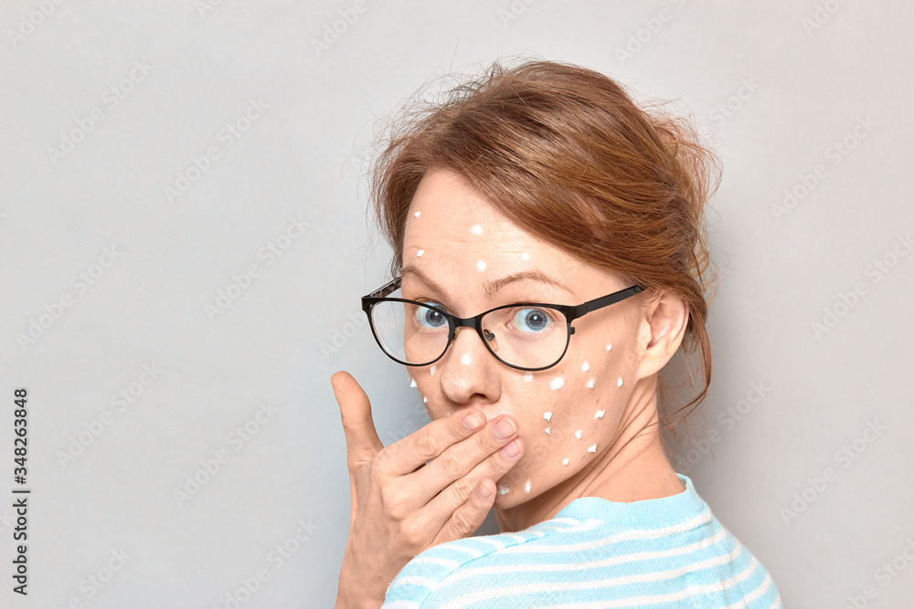 Portrait of surprised girl with white drops of face cream on skin Portrait of surprised girl with white drops of face cream on skin