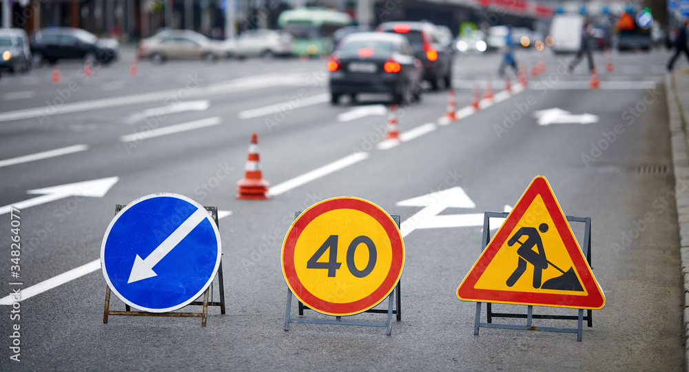 Road marking on the road, warning signs and orange safety cones on background. Direction of detour, sign speed limit 40 and roadworks. Road signs denoting road repairs, speed limit up to 40, detour Road marking on the road, warning signs and orange safety cones on background. Direction of detour, sign speed limit 40 and roadworks. Road signs denoting road repairs, speed limit up to 40, detour