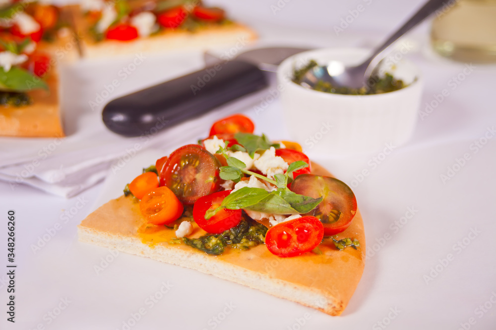 Homemade pizza with cherry tomatoes, fresh green basil and feta cheese. Homemade food. Concept for a tasty and hearty meal. Wooden background. Close up.