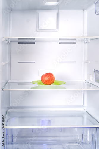 Empty fridge with single red apple inside