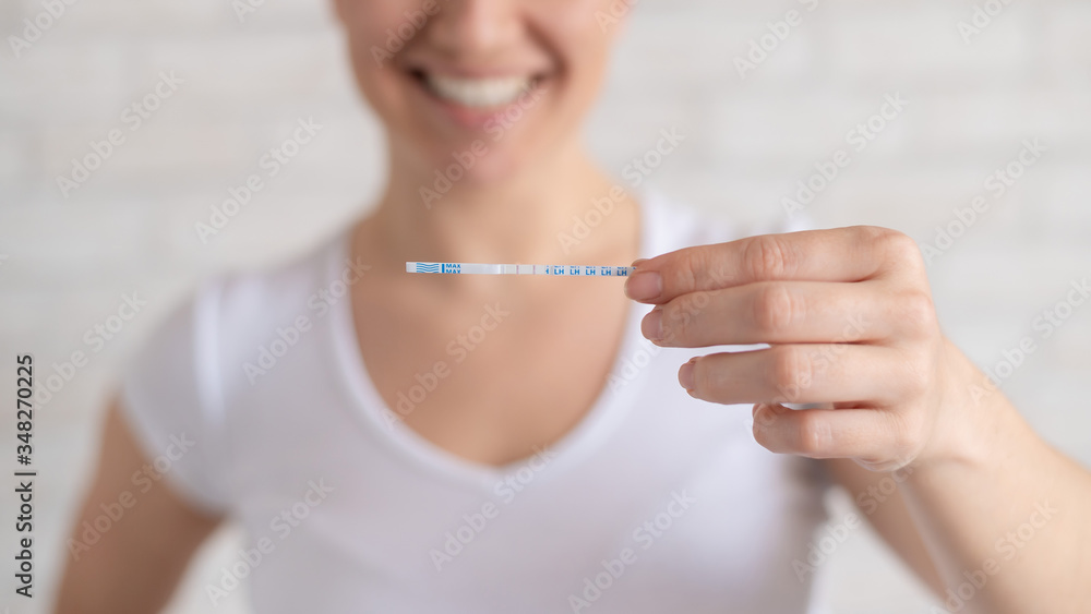 Happy woman shows a positive ovulation test. The concept of female fertility and high luteinizing hormone. The right time to conceive a child. Happy woman shows a positive ovulation test. The concept of female fertility and high luteinizing hormone. The right time to conceive a child.