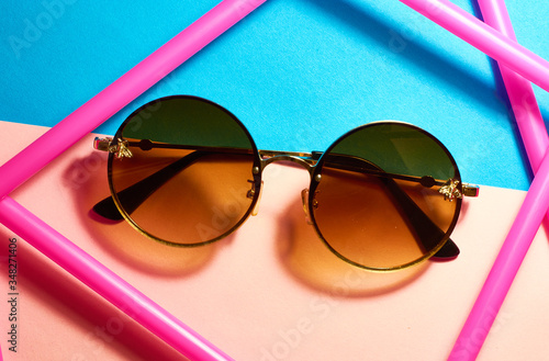 Round, female, with brown lenses, sunglasses on pink background.