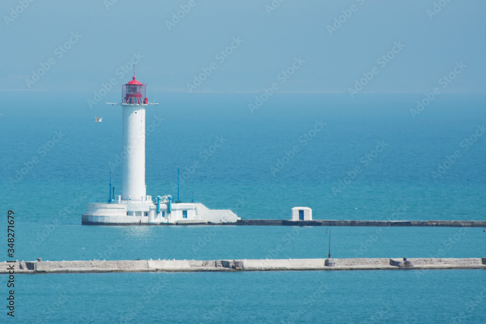 View of the white lighthouse in the seaport. Seascape on a summer morning.