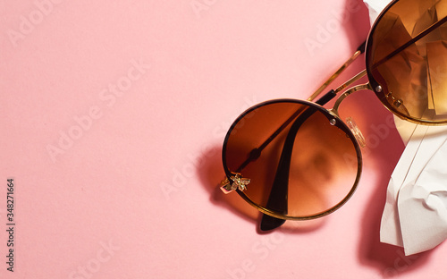 Round, female, with brown lenses, sunglasses on pink background.
