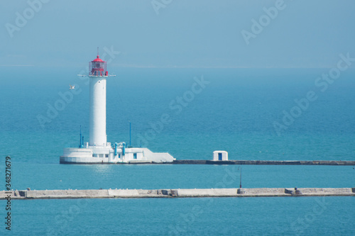 View of the white lighthouse in the seaport. Seascape on a summer morning. © imartsenyuk
