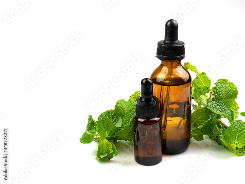 Peppermint essential oil in a separate bottle on a white background, herbs rich in vitamins and minerals such as Beta-carotene, calcium, vitamin B2 and 3.
