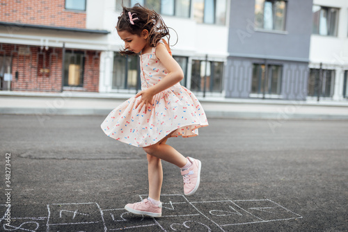 Konstfotografi Horizontal image of little girl playing hopscotch on playground outdoors