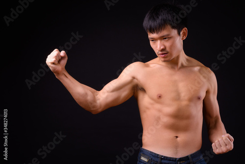 Portrait of young muscular Asian man shirtless ready to fight