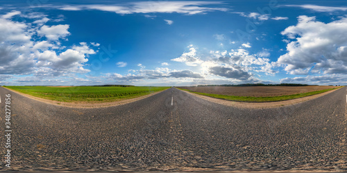 Full spherical seamless panorama 360 degrees angle view on no traffic asphalt road among fields in evening before sunset with cloudy sky in equirectangular projection, VR AR content