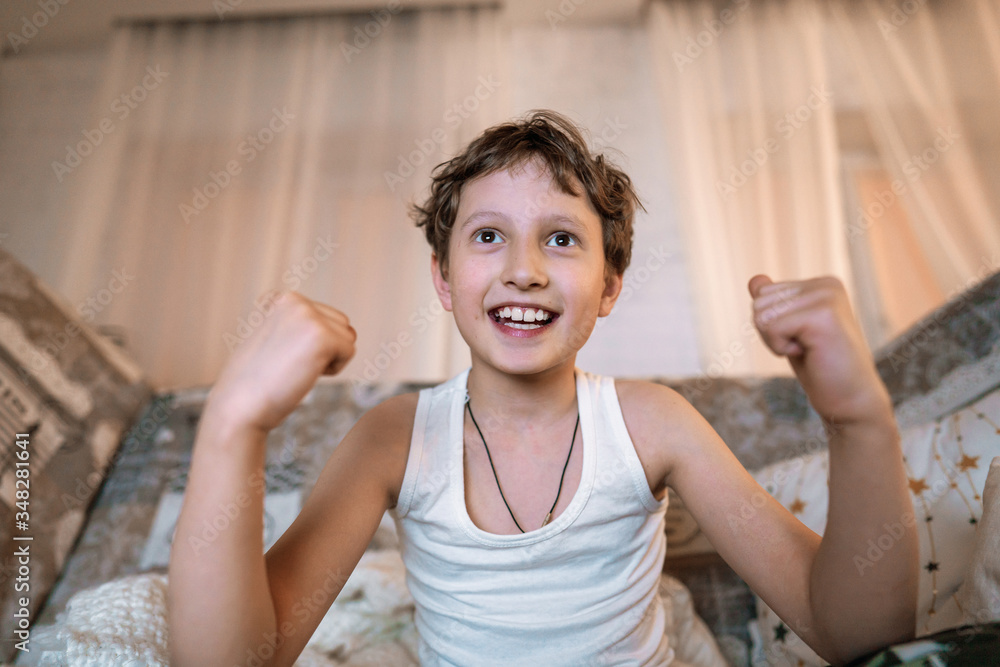 cheerful boy enthusiastically watches TV in the evening. cheerful boy enthusiastically watches TV in the evening.