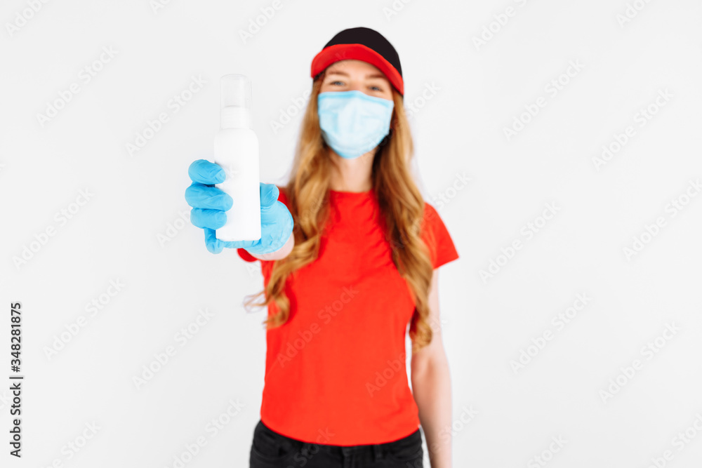 A courier in uniform, medical rubber gloves and a mask, holding a disinfectant on a white background. Online stores quarantine, coronavirus A courier in uniform, medical rubber gloves and a mask, holding a disinfectant on a white background. Online stores quarantine, coronavirus