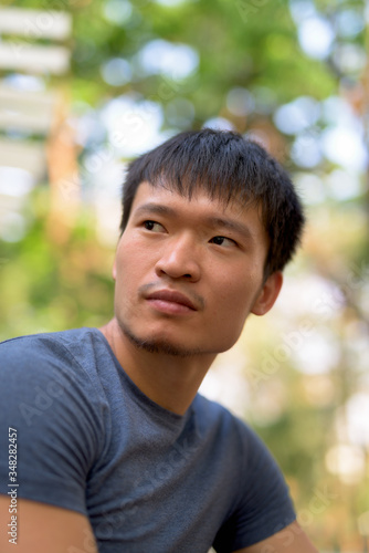 Portrait of young Asian man thinking at the park outdoors