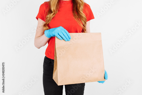 The courier holds a paper bag with food on an isolated white background. Fast and free delivery. Express delivery