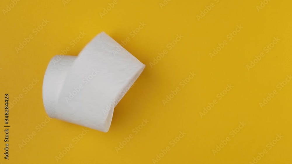 Roll of toilet paper falling on the yellow background. Slow motion, top view Roll of toilet paper falling on the yellow background. Slow motion, top view