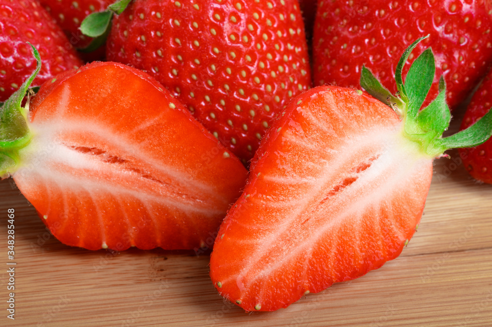 Ripe fresh strawberries, whole and cut into slices on a wooden Board very close-up. Ripe fresh strawberries, whole and cut into slices on a wooden Board very close-up.