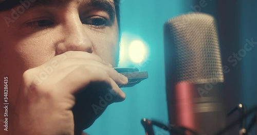Close-up Musician in headphones playing on harmonica at home sitting on floor at evening time. Music hobby, Create own songs, learning online. Social distancing, 4K video
