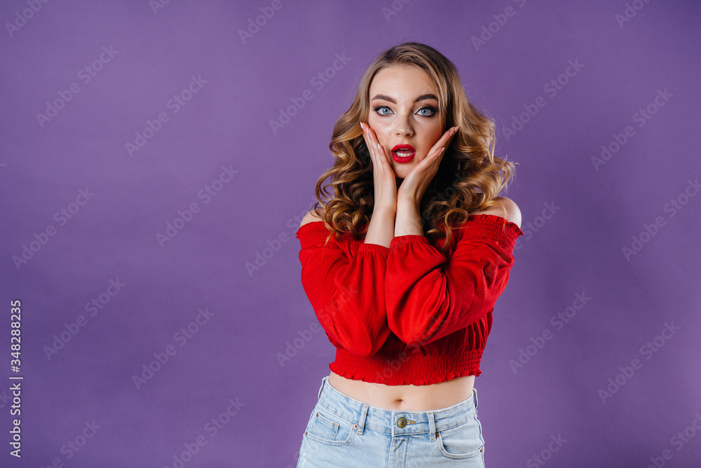 A young beautiful girl shows emotions and smiles in the Studio on a purple background. Girls for advertising A young beautiful girl shows emotions and smiles in the Studio on a purple background. Girls for advertising