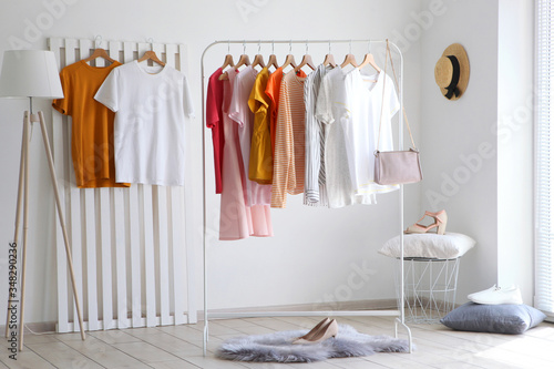 fashionable clothes on a rack in the interior of a bright room 