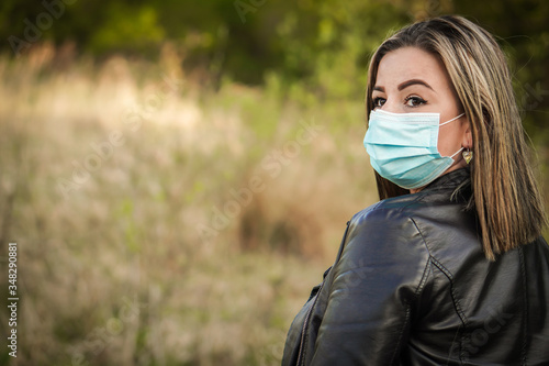 Young blonde hair woman with her face mask on the walking in the park. She is looking forward to the end of corona virus - COVID 19 and quarantine. © Nataly