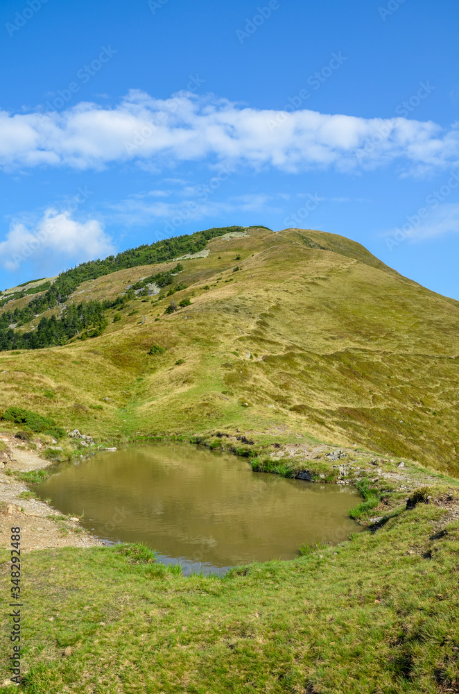 Beautiful mountain landscape, clouds on the blue sky with high green hills, rocks and lake. Carpathians, Ukraine