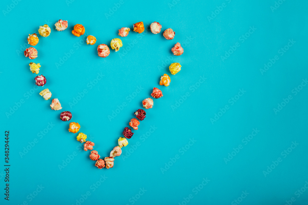 Heart laid out of corn kernels on a blue background.