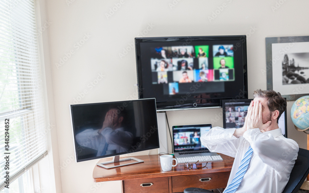 Man working from home showing emotion with hands on face during virtual computer video chat meeting. 