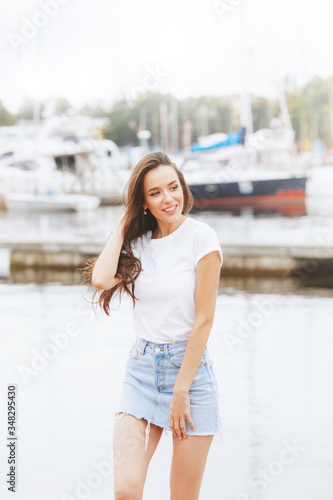 Young beautiful happy woman walks on beach in marina