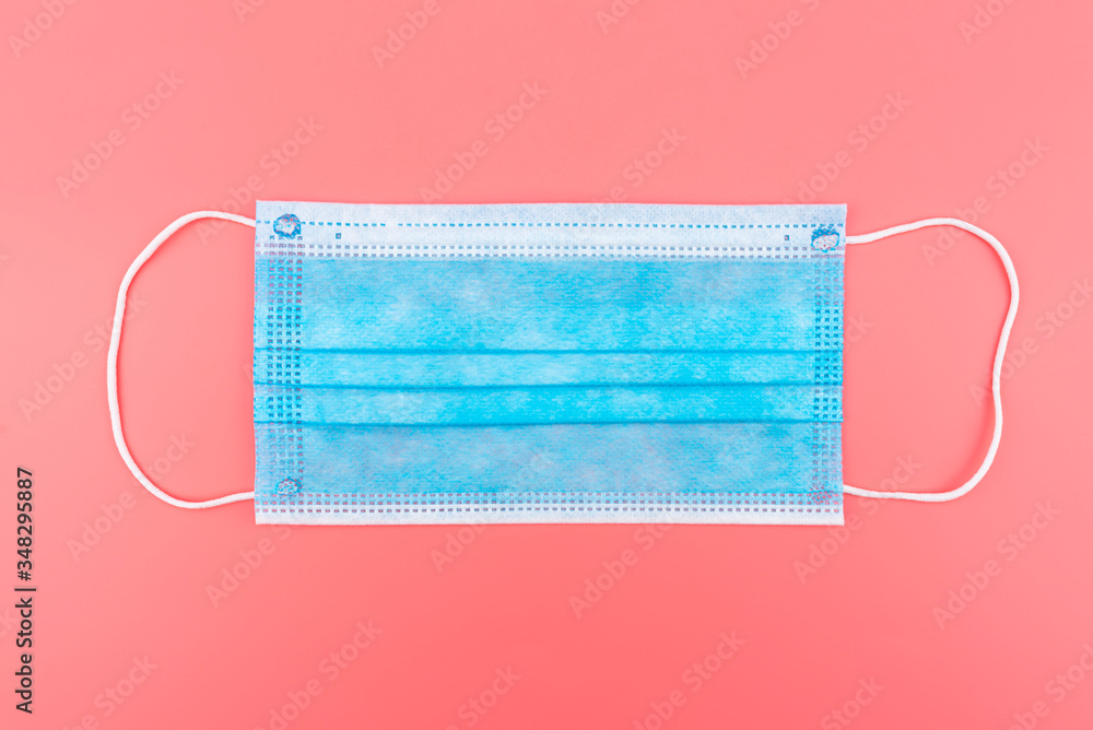 Disposable blue surgical mask, isolated on a pink background, top view. Disposable blue surgical mask, isolated on a pink background, top view.