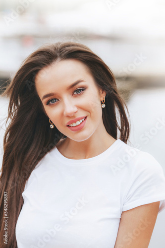 Young beautiful happy woman walks on beach in marina