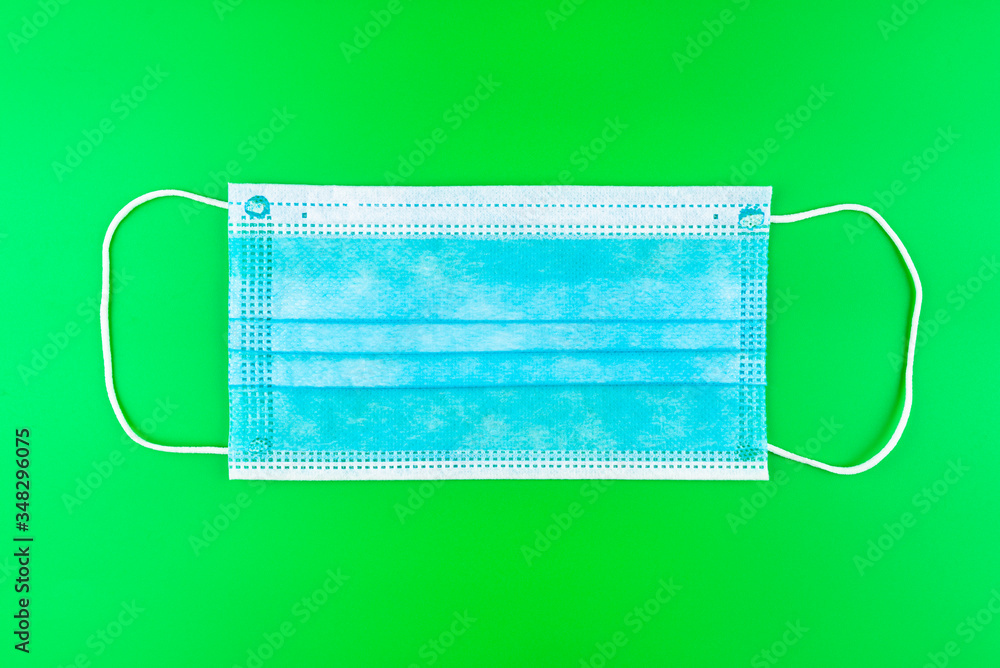 Disposable blue surgical mask, isolated on a green background, top view. Disposable blue surgical mask, isolated on a green background, top view.