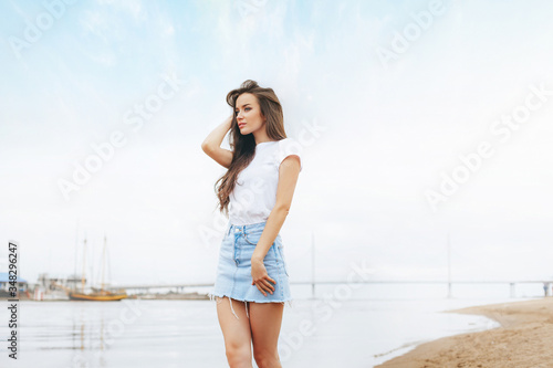 Young beautiful happy woman walks on beach in marina