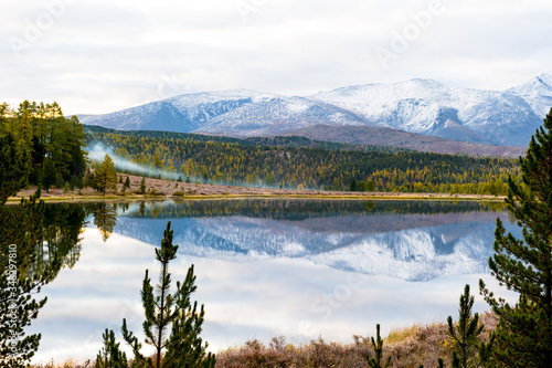 Lake  Altai  Siberia  cloudy autumn day. Taiga  beautiful sky  haze  snow-capped mountains