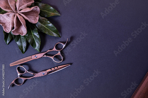 Bild auf Leinwand scissors for a hairdresser and decoration made of wood and leaves lie on a textu
