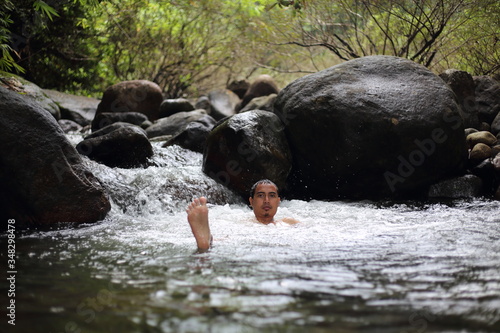 A man is bathing in the Trok Nong waterfall in Chanthaburi, Thailand. photo