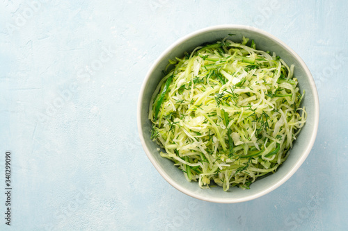 Fresh cabbage and cucumber salad with dill in bowl on concrete background. Coleslaw.