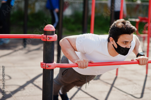 Portrait sports arabian man in black medical face mask doing workout exercises in outdoor gym place during coronavirus quarantine. © AS Photo Family