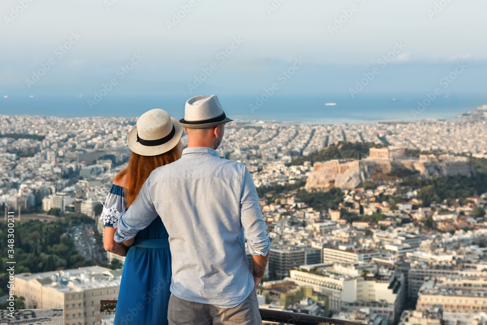 
A couple in love with tourists standing on Mount Likavitos in Athens at dawn. The best panorama of Athens and the Acropolis. In the background the Aegean Sea.