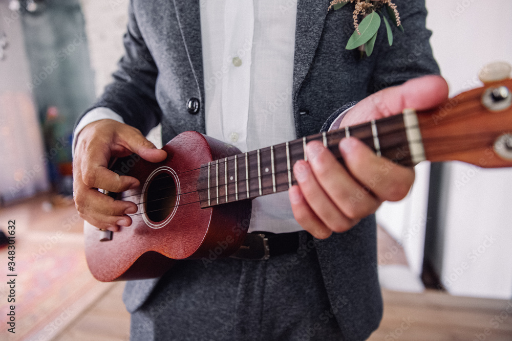 Guitar with hands of the groom, close-up. Ukulele, hands of the groom with wedding ring. Romance, love, family.