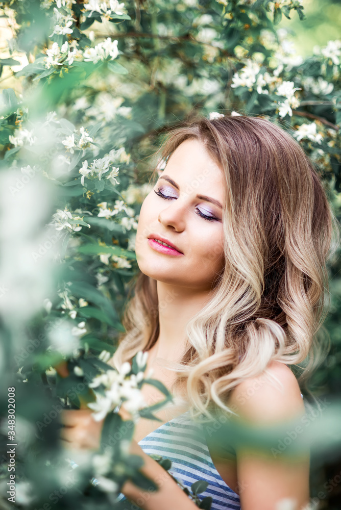 Beautiful young woman in a blooming garden. Close-up portrait of a girl with closed eyes Beautiful young woman in a blooming garden. Close-up portrait of a girl with closed eyes