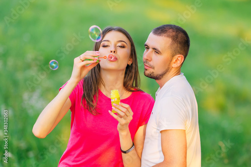girl with makeup blowing soap bubbles and the guy looks at them.