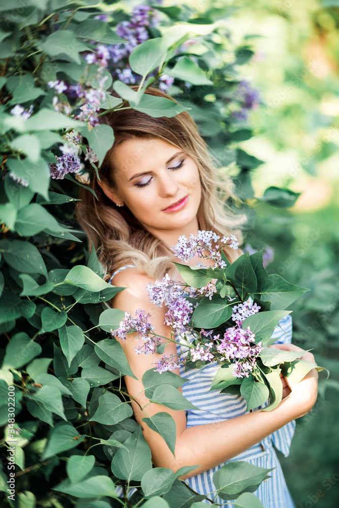 A beautiful happy young woman enjoys the smell in a blooming spring Lilac garden. A beautiful happy young woman enjoys the smell in a blooming spring Lilac garden.