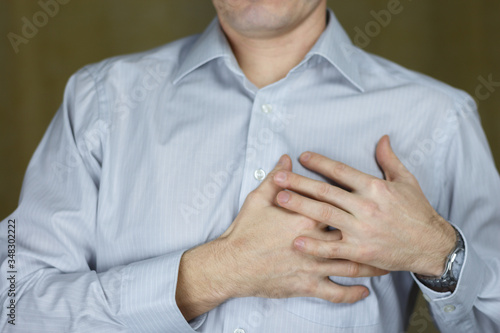 Palms on the right side of the male chest in a shirt. Problems with heart. Selective focus.