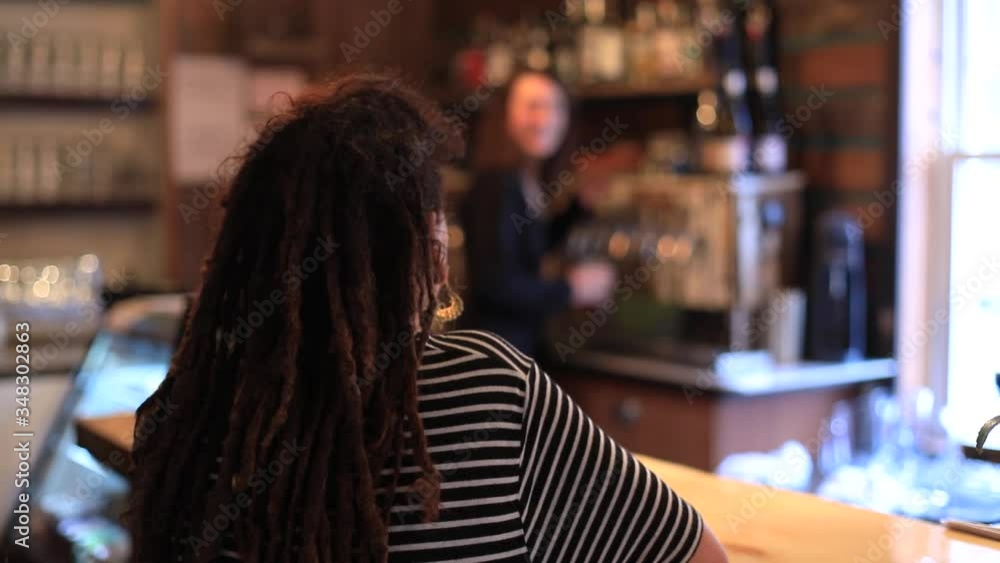 Rear view of young female customer waiting in touristy village brewery pub for wine and bartender filling glass with wending machine and serving glass Rear view of young female customer waiting in touristy village brewery pub for wine and bartender filling glass with wending machine and serving glass