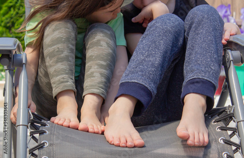 the children going barefoot in a lawn chair. The concept of relaxation. Legs close up